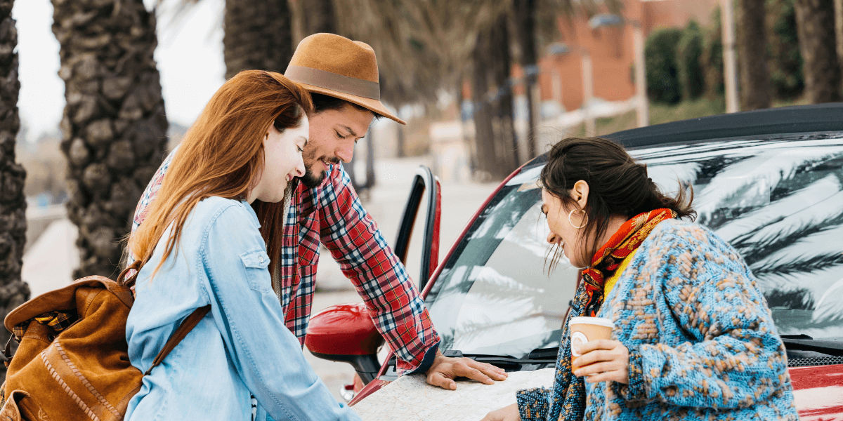 Friends discussing a map on the car bonnet, planning their route.