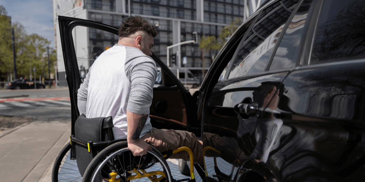 A man in a wheelchair beside a taxi, ready for an accessible ride.